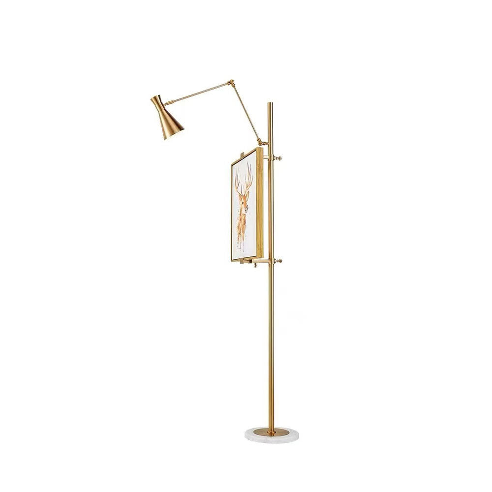 Clérachic gold floor lamp seen from the side, with a framed picture on the pole and an angled arm and cone shade at the top.