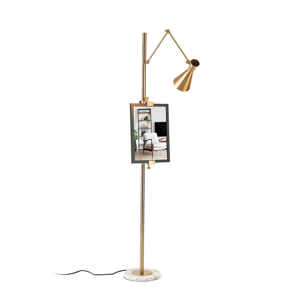 A Clérachic gold floor lamp with a framed picture on its pole and a black cord trailing from the marble base, on a white backdrop.
