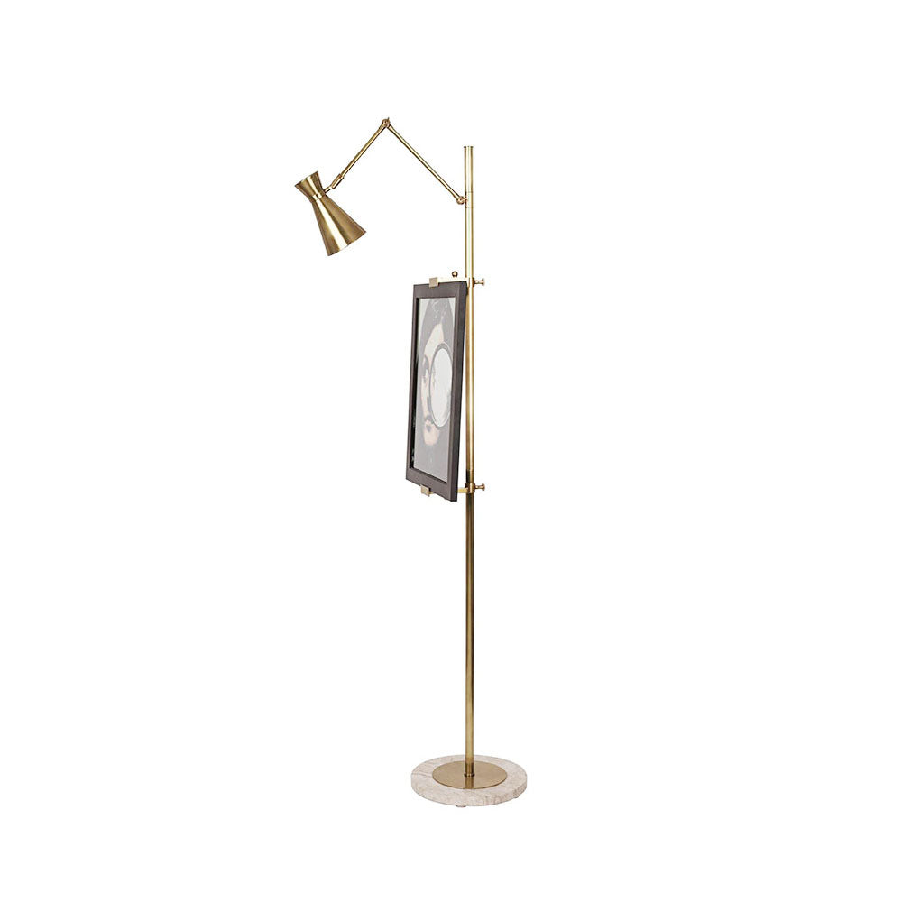 Side view of a Clérachic gold floor lamp with a framed picture clipped to its pole, on a white backdrop.