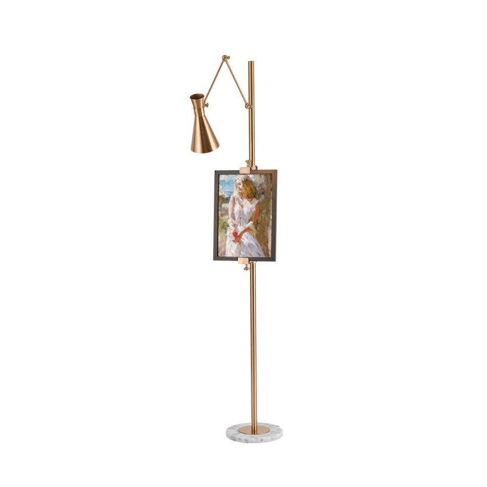 Small view of a Clérachic gold floor lamp with a framed portrait and a cone shade on a long arm, above a marble base on white.