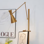 Cone shade and arm joint of this Clérachic floor lamp lit above a framed line drawing, with a large print behind it.