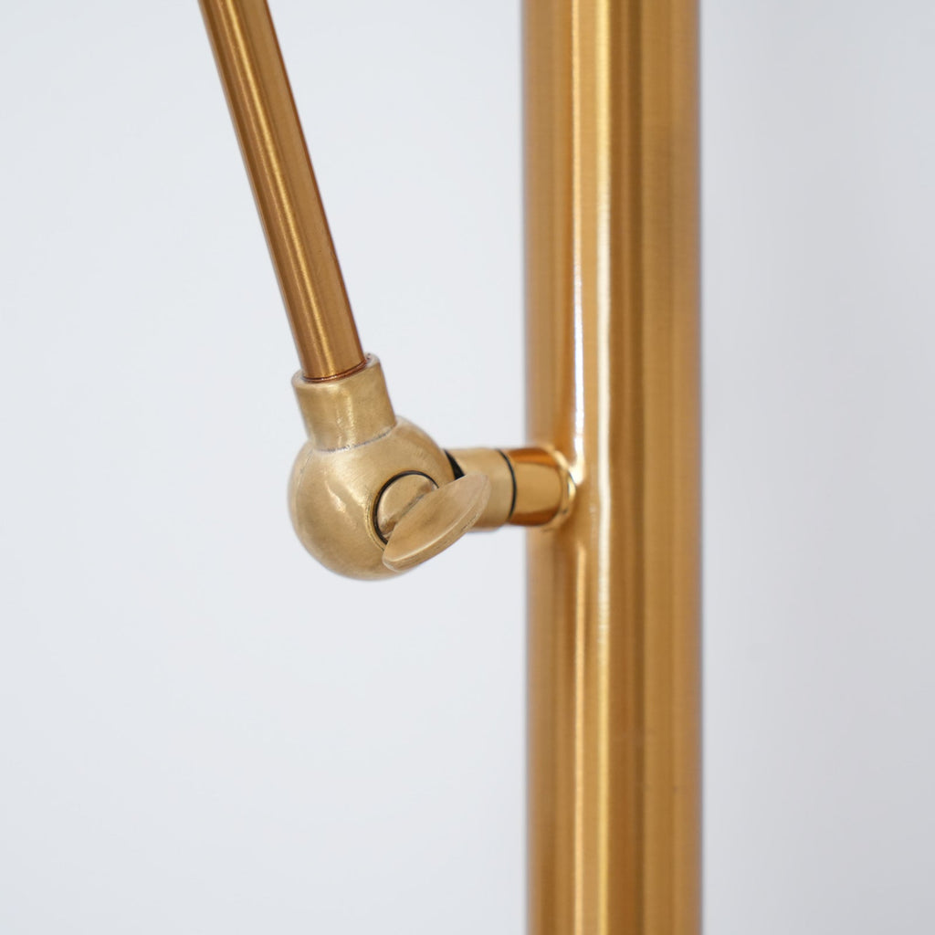Close view of the ball joint where the angled arm meets the gold pole on this Clérachic floor lamp.