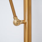 Close view of the ball joint where the angled arm meets the gold pole on this Clérachic floor lamp.