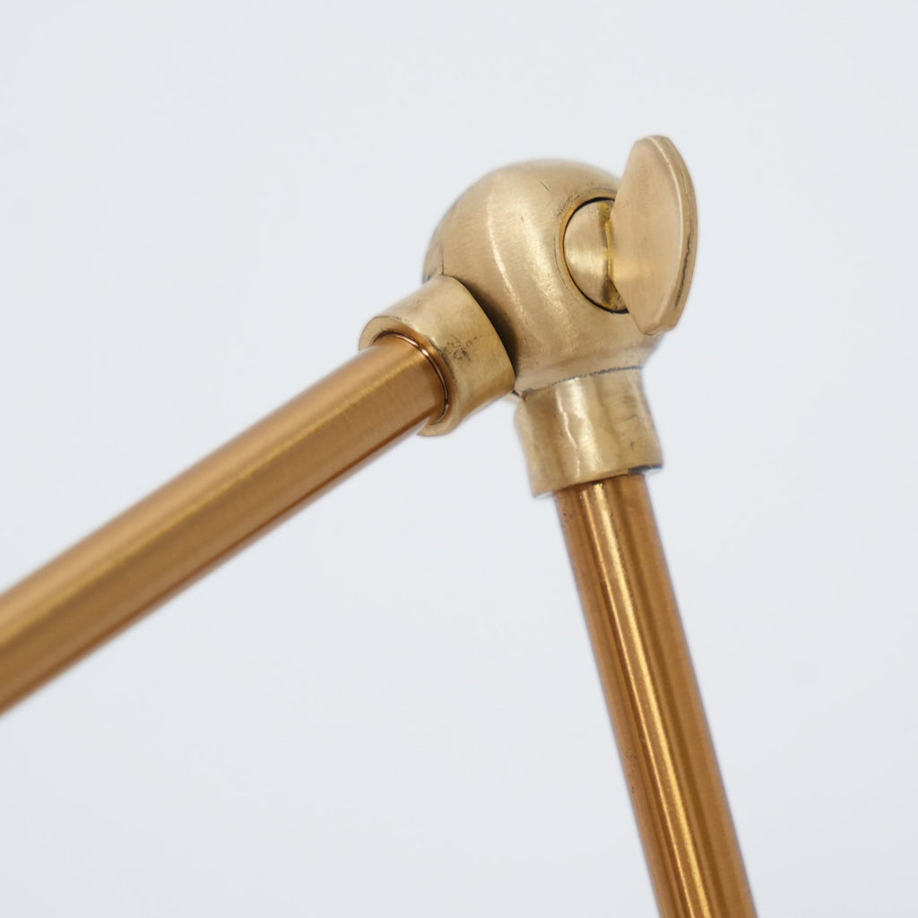 Close view of the brass ball joint and tightening knob on the arm of this Clérachic floor lamp.