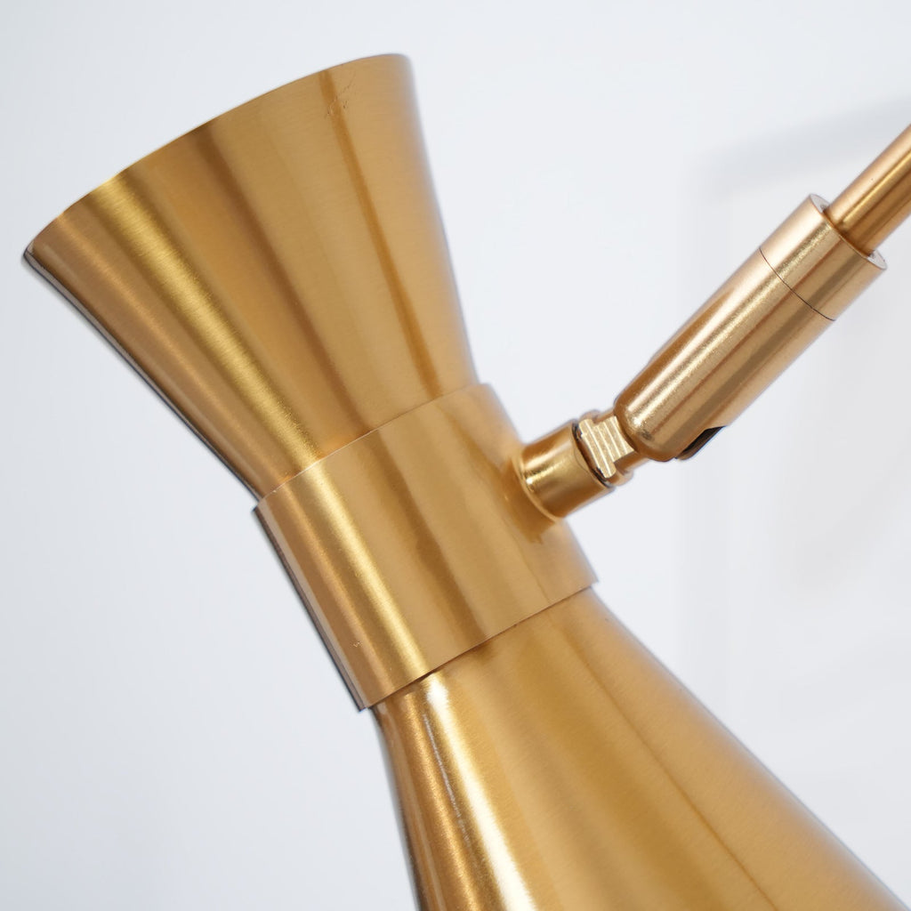 Close view of the hourglass-shaped gold cone shade on this Clérachic floor lamp and its small hinge to the arm.