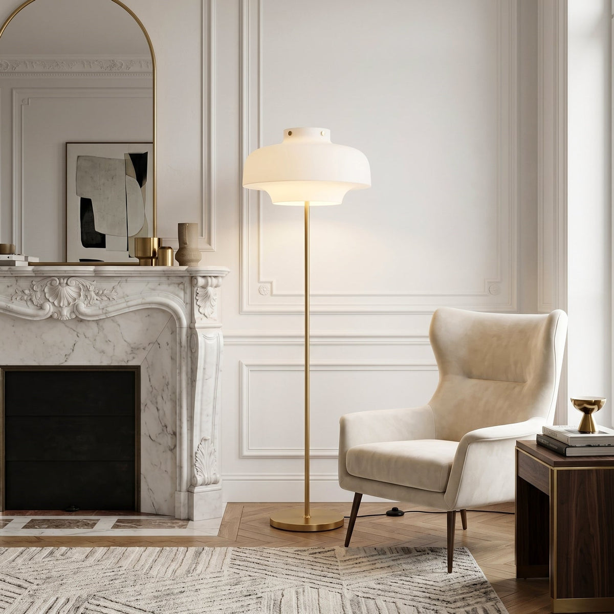 Beside a white marble fireplace and a cream wing chair, this Clérachic floor lamp glows softly, its brass stem rising from a round base.