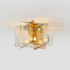 Lit Clérachic ceiling light seen from below, with amber and clear glass panes throwing a warm glow across a pale ceiling.