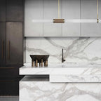 Close crop of this Clérachic pendant light above a white marble island, its gold-and-wicker centre band set against grey cabinetry.