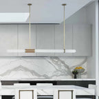 Hung in a pale kitchen with a skylight, this Clérachic pendant light runs level above the marble-backed counter.