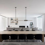 This Clérachic pendant light floats above a long timber table in an open-plan room, black chairs lined up beneath it.