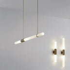 This Clérachic pendant light hangs at a slant on gold rods, two lit wall lights glowing at the lower right.