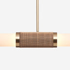 Close view of the woven rattan-look band and gold collars on this Clérachic pendant light, with the frosted tube glowing on each side.