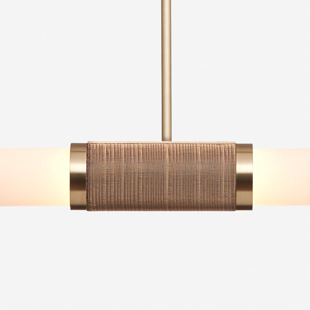 Close view of the woven rattan-look band and gold collars on this Clérachic pendant light, with the frosted tube glowing on each side.