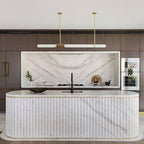 This Clérachic pendant light hangs over a fluted white marble island, with a recessed marble splashback and oak cabinetry behind.
