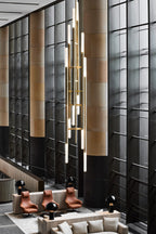 A closer look at the tall vertical cluster of this Clérachic pendant light in a lobby, tubes lit at several heights.