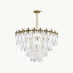 A Clérachic chandelier on a plain white backdrop, with overlapping clear glass leaf shades under a gold crown and a gold canopy on a chain.