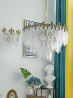 Angled view of this Clérachic chandelier with a matching wall light beside it, near a teal and yellow curtain and a white bust on a table.