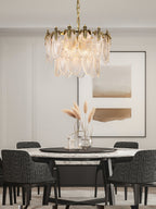 This Clérachic chandelier hangs over a round marble dining table with dark woven chairs and dried pampas grass in a glass vase.