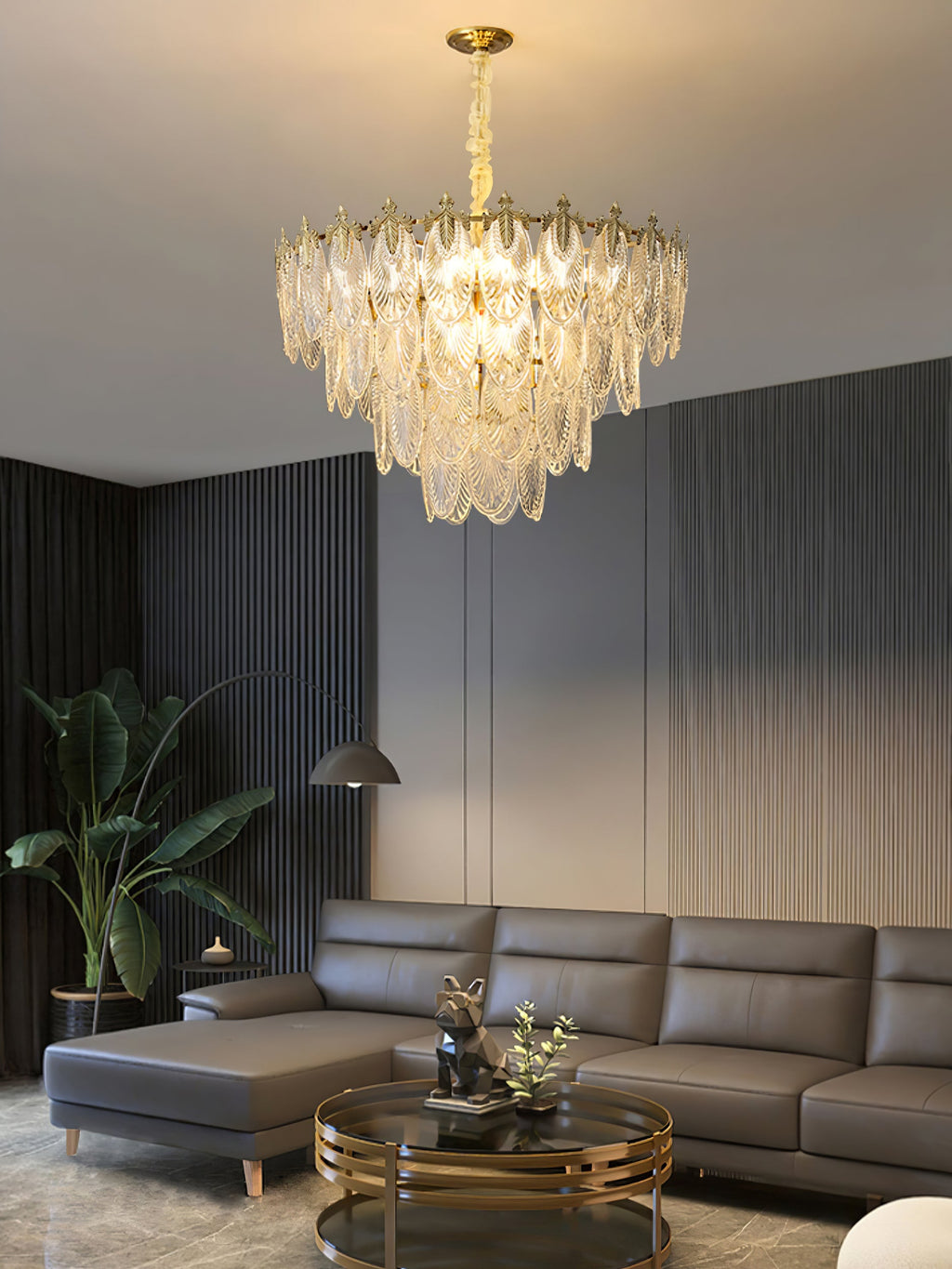 Lit Clérachic chandelier in a dark lounge with grooved wall panels, a grey leather corner sofa and a round glass coffee table.