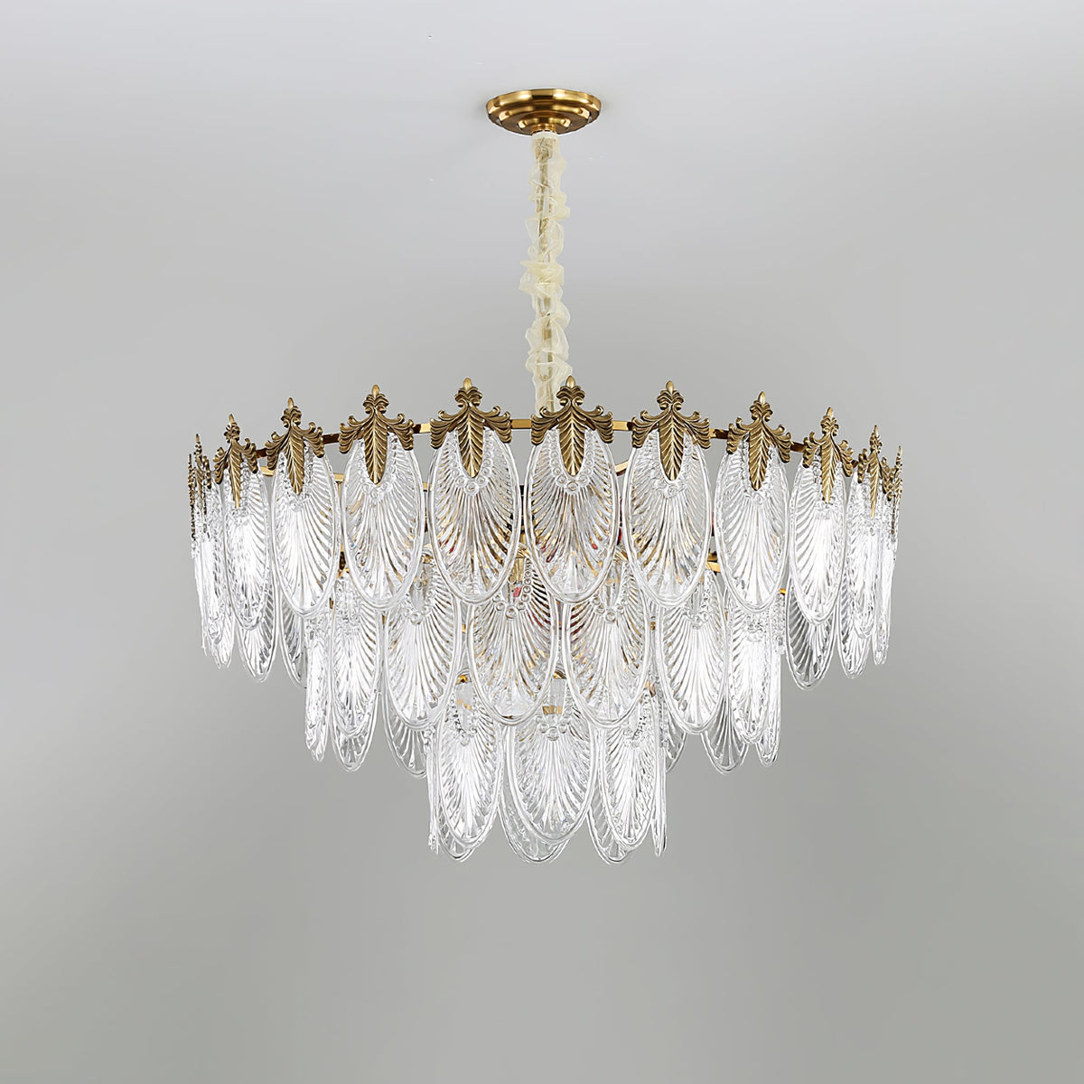 Broad, shallow three-tier Clérachic chandelier on a grey backdrop, with clear glass leaves and a gold crown, unlit.
