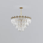 Mid-size three-tier Clérachic chandelier with clear glass leaves under a gold crown, hanging from a short chain on a light grey backdrop.