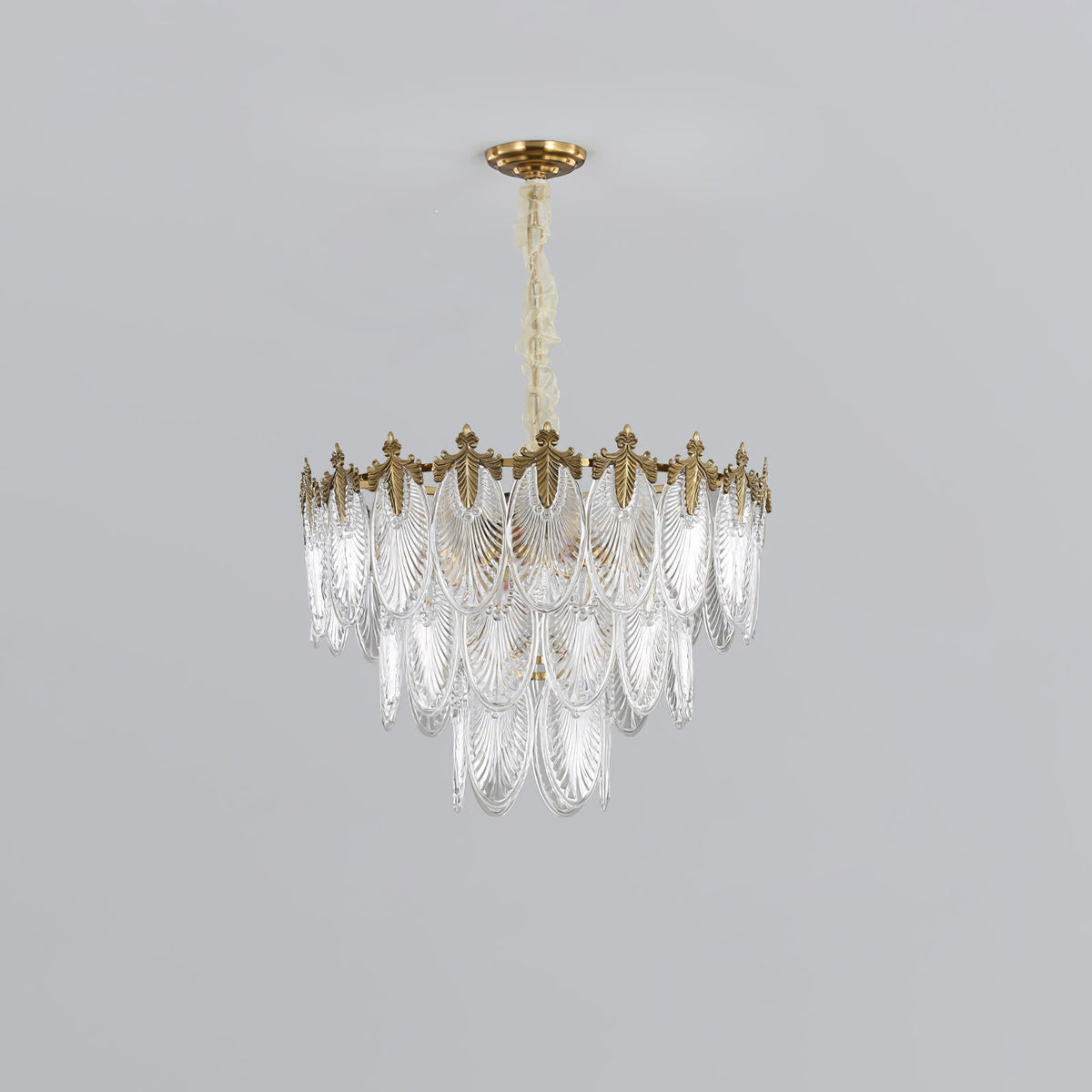 Compact three-tier Clérachic chandelier on a light grey backdrop, its glass leaves tapering below the gold crown, unlit.