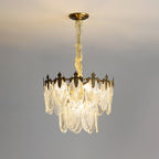 Two-tier Clérachic chandelier lit on a grey backdrop, with a long pale chain and glass leaves glowing at the lower edge.