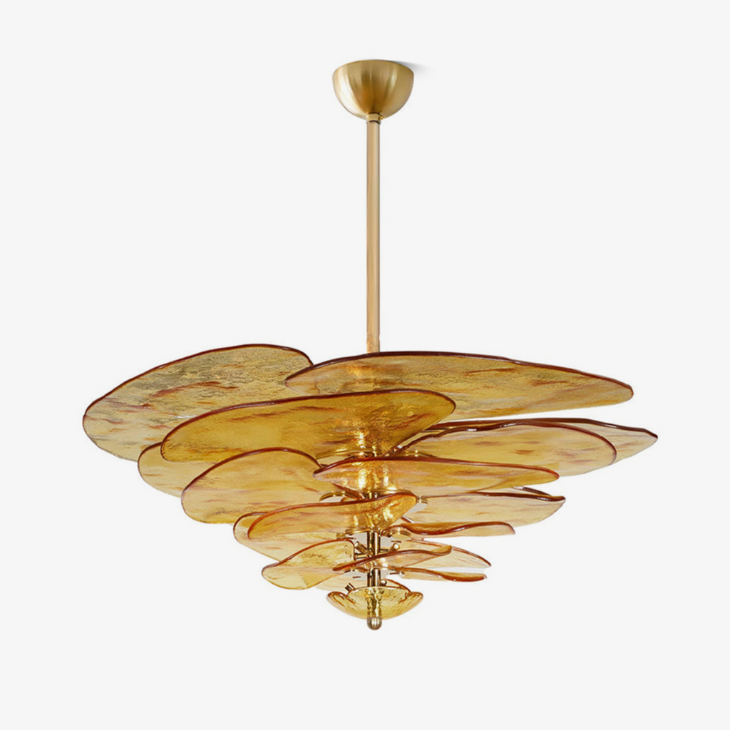 A Clérachic chandelier on a white backdrop, with amber-gold glass petals stacked in tiers around a brass rod and a brass ceiling cup.