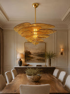 Amber Clérachic chandelier lit over a long wooden dining table in a panelled room, with a landscape painting on the far wall.