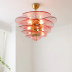 Close view of a pink and gold Clérachic chandelier lit against a white ceiling, with its petals layered around a brass cup.