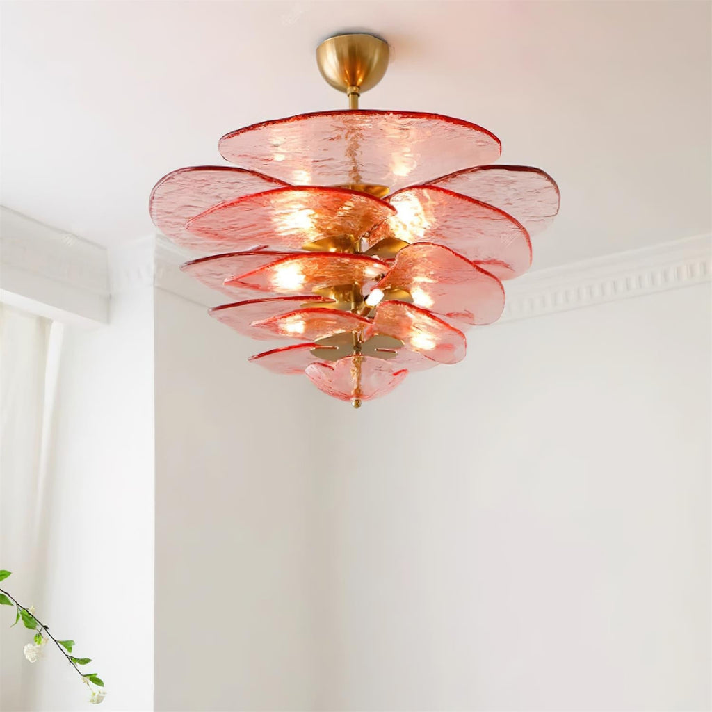 Pink and gold Clérachic chandelier lit from a low angle, its glass petals glowing orange where the bulbs sit between them.