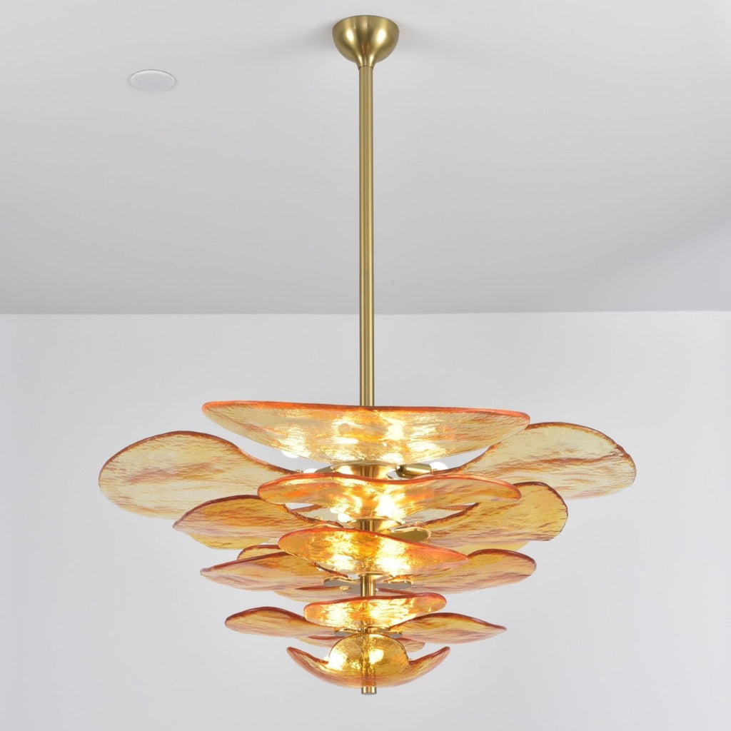 Amber Clérachic petal chandelier on a long brass rod, with orange-edged glass tiers narrowing towards the bottom, on a grey backdrop.