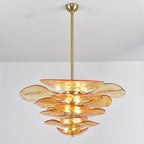 Amber Clérachic petal chandelier on a long brass rod, with orange-edged glass tiers narrowing towards the bottom, on a grey backdrop.