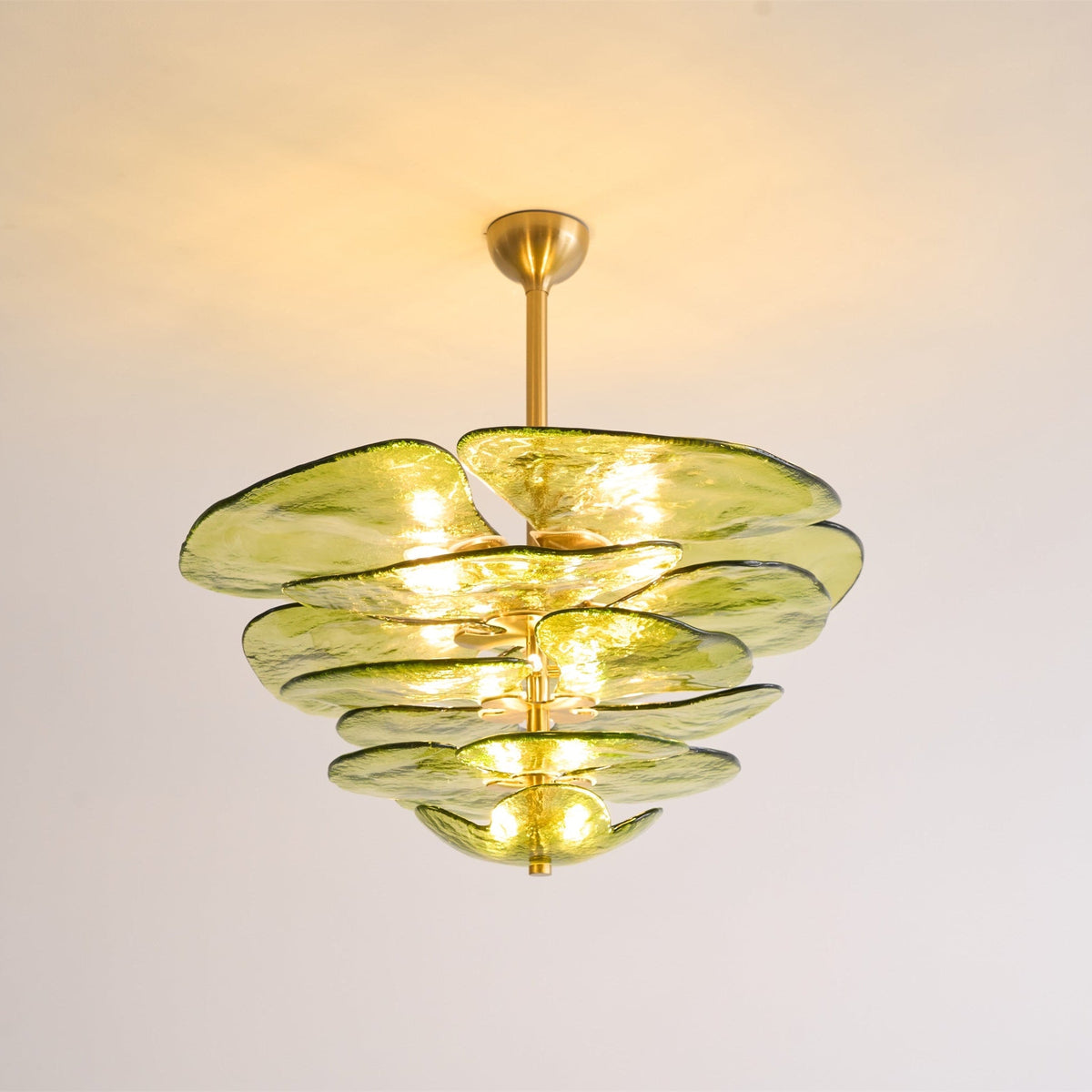 Green Clérachic chandelier on a short brass rod, lit, with warm light across the ceiling and olive glass petals below.
