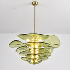 Green Clérachic chandelier on a long brass rod, lit, with its glass petals of different sizes spread in loose tiers.