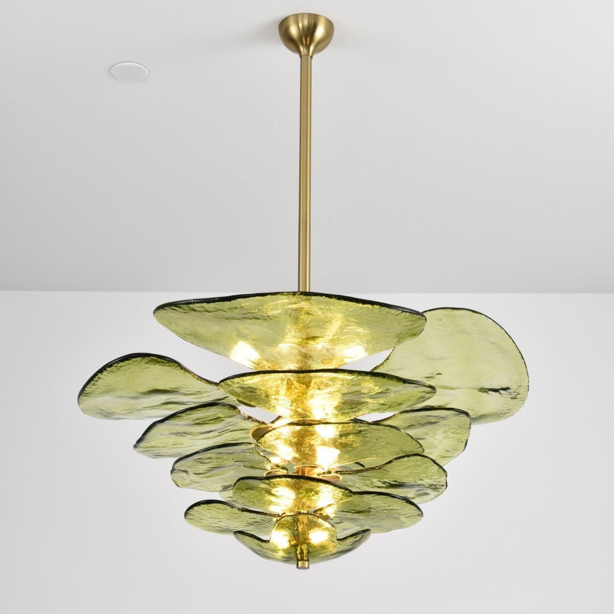 Green Clérachic chandelier on a long brass rod, lit, with its glass petals of different sizes spread in loose tiers.