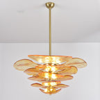 Lit amber Clérachic chandelier on a long brass rod, its glass petals shading from pale gold to orange at the edges.