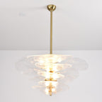 Lit clear glass Clérachic chandelier on a long brass rod, with soft white petals and bulbs glowing between the tiers.