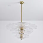 Unlit clear glass Clérachic chandelier on a long brass rod, its rippled petals stacked and a brass spindle visible in the centre.