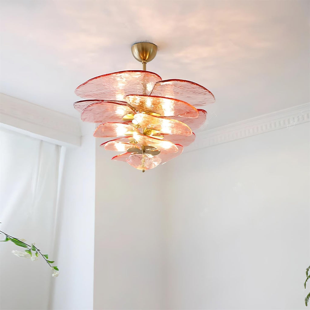 Pink Clérachic petal chandelier glowing near a white corner ceiling, with its bulbs showing between rippled red-edged glass discs.