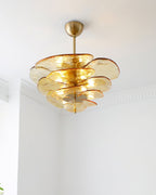 Amber Clérachic chandelier lit in a white corner, with pale gold glass petals and a short brass rod below the ceiling cup.