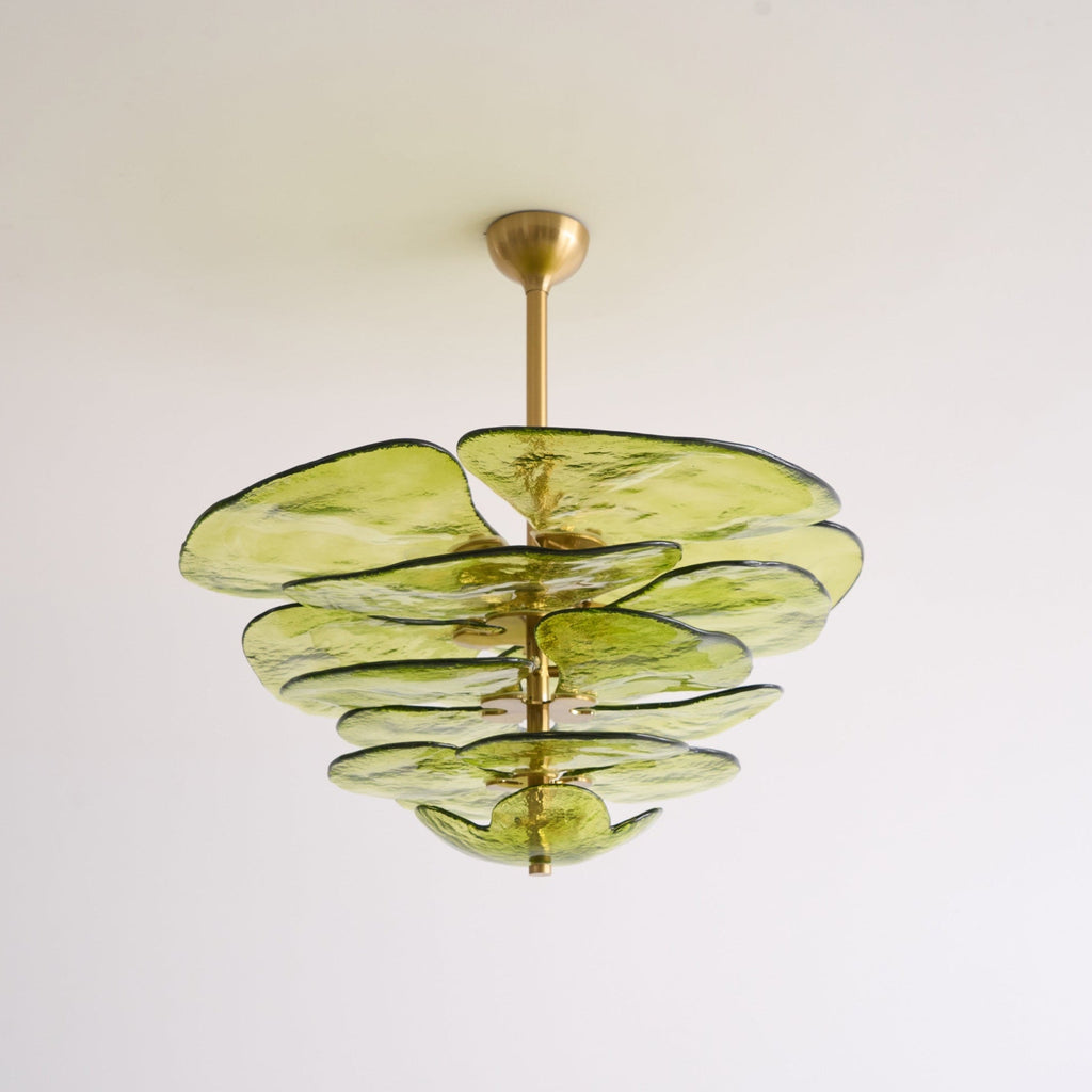 Unlit green Clérachic chandelier on a white backdrop, its olive glass petals layered below a short brass rod and cup.