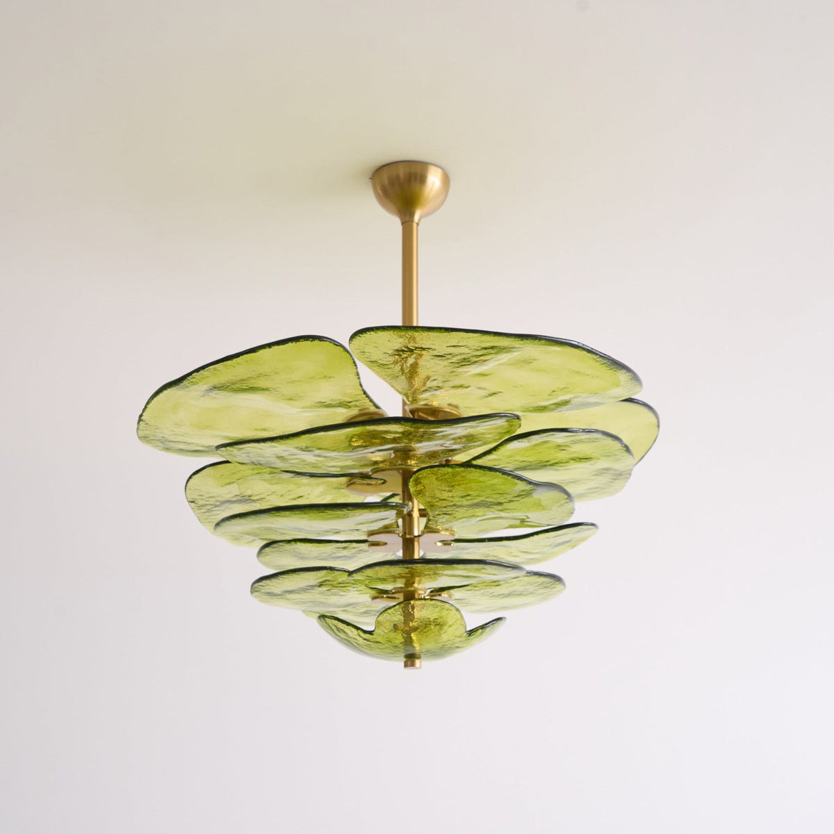 Unlit green Clérachic chandelier on a white backdrop, its olive glass petals layered below a short brass rod and cup.