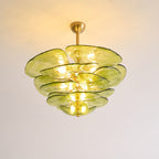 Lit green Clérachic chandelier on a warm-toned ceiling, with bulbs glowing between its olive glass petals.