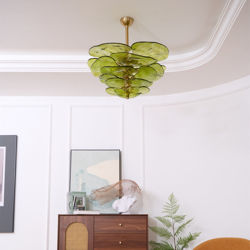 Small green Clérachic chandelier high in a curved white room, above a framed print and a cabinet with a cane panel.