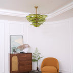 Wide room view with a small green Clérachic chandelier on the ceiling, a cane-fronted cabinet, a fern and a mustard armchair.