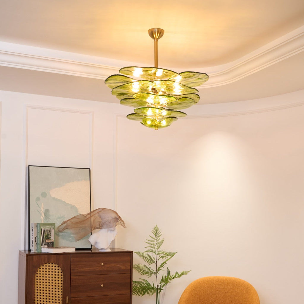 Lit green Clérachic chandelier in a room with a coved ceiling, a framed print, a glass sculpture and a fern beside a cabinet.