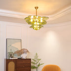 Lit green Clérachic chandelier in a room with a coved ceiling, a framed print, a glass sculpture and a fern beside a cabinet.