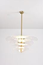 Clear glass Clérachic chandelier lit brightly on a grey backdrop, its pale tiers glowing from the bulbs inside.