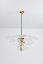 Unlit clear glass Clérachic chandelier with gold fittings on a grey backdrop, its tiers of petals hung from a long brass rod.